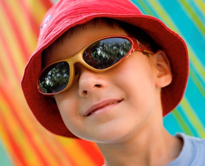 young boy in a hat and sunglasses at the beach