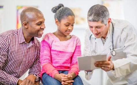 African american father and daughter talking to pediatrician