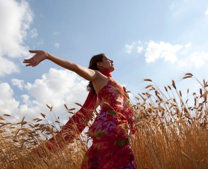 happy woman walking through wheat