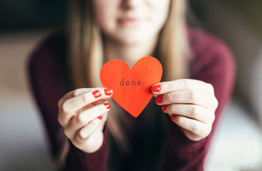 Young teen girl holding heart shaped paper cutout with the Spanish  word for "give" written on it.