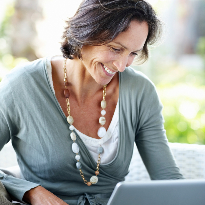 Smiling, middle-aged woman at home working on a laptop computer